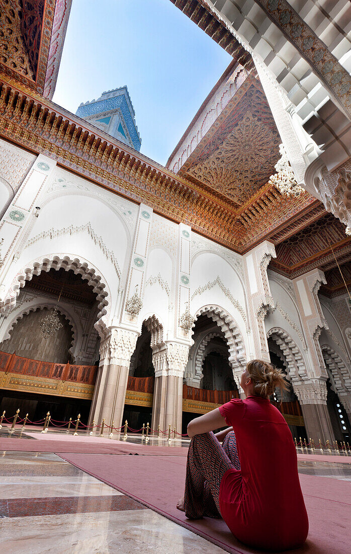 Woman staring upwards through the open roof in the Hassan II mosque, Casablanca, Morocco