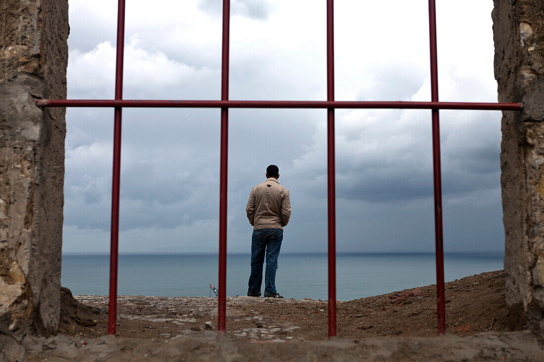 Man looking out over the Straits of Gibraltar from the Borj Dar el-Baroud, Tangiers, Morocco