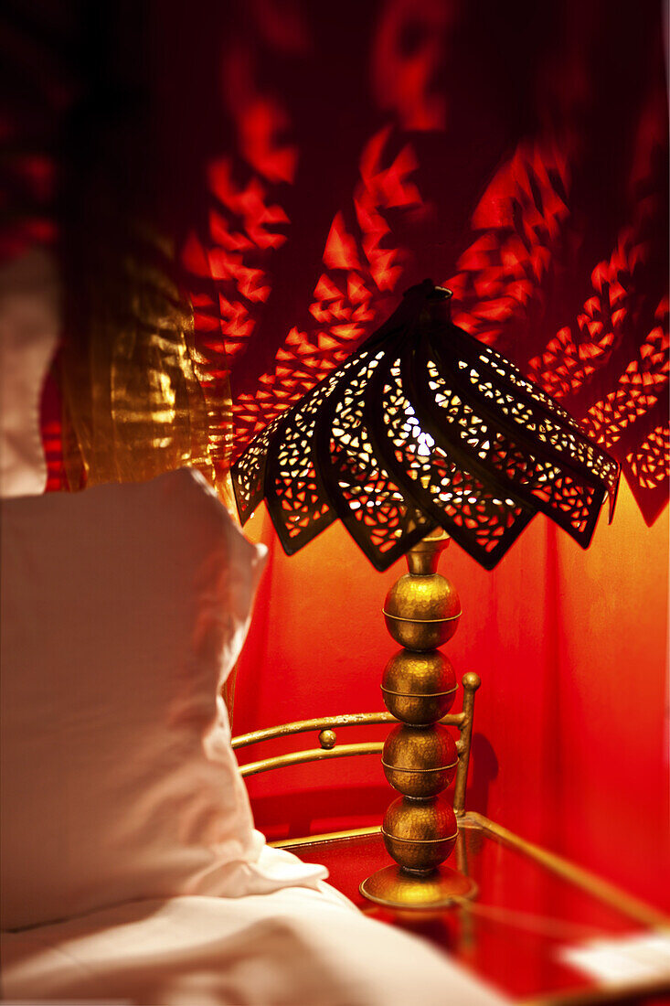 Lamp making dappled shadows over bed, guest room, Dar Les Cigognes, Marrakech, Morocco