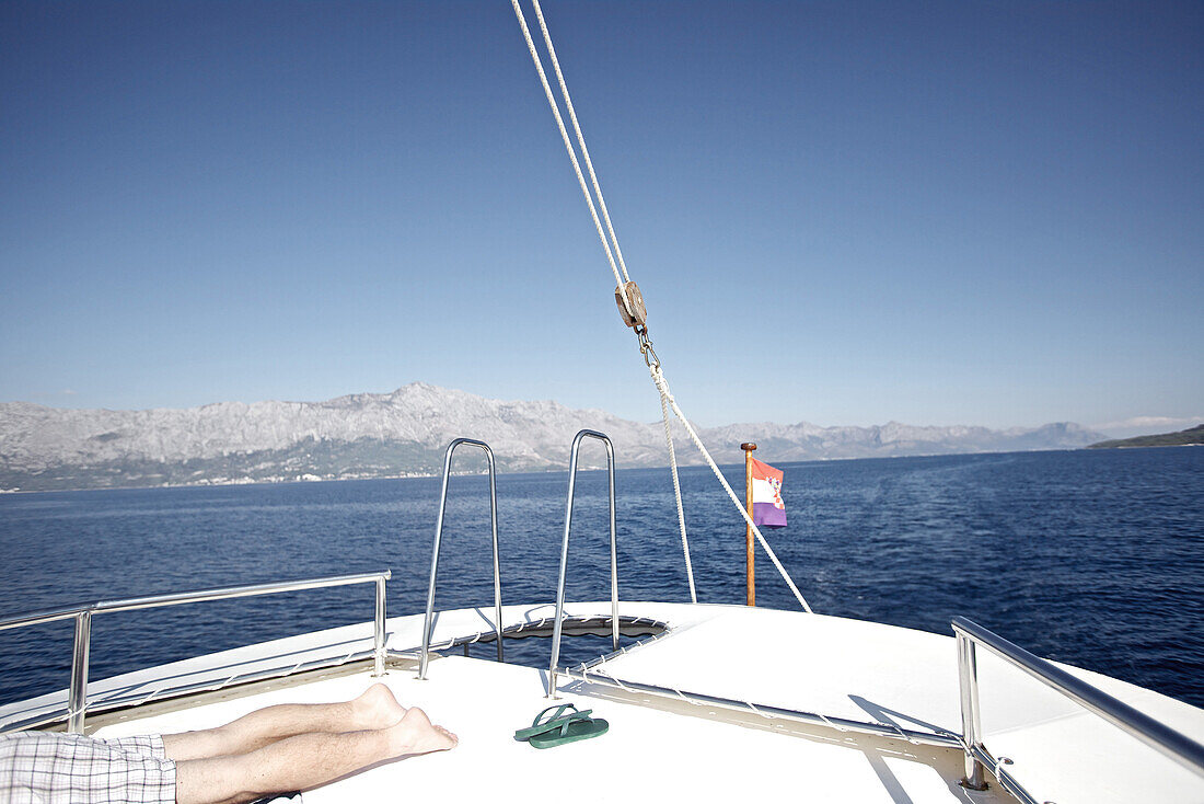 Person liegt auf einem Segelboot auf dem Meer, Hvar, Dalmatien, Kroatien