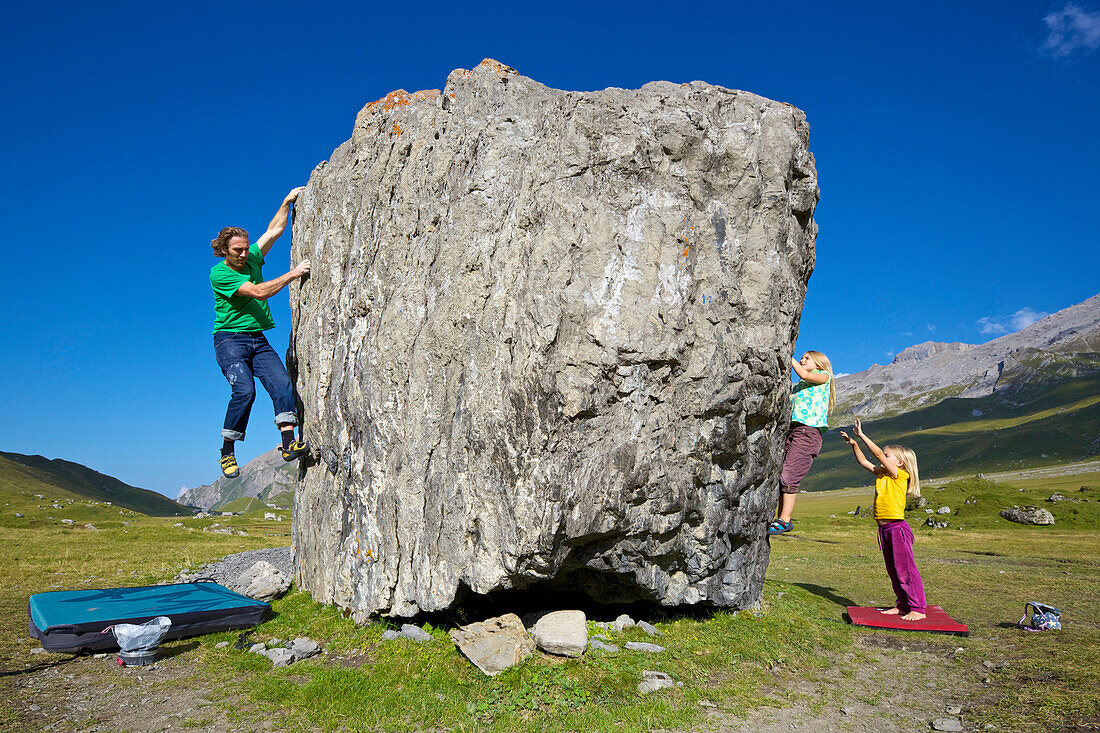 Two girls and a man bouldering, climbing, Engstligenalp, Bernese Oberland, Switzerland