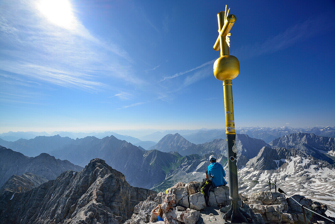 Person sitzt am Gipfel der Zugspitze, Wettersteingebirge, Oberbayern, Bayern, Deutschland