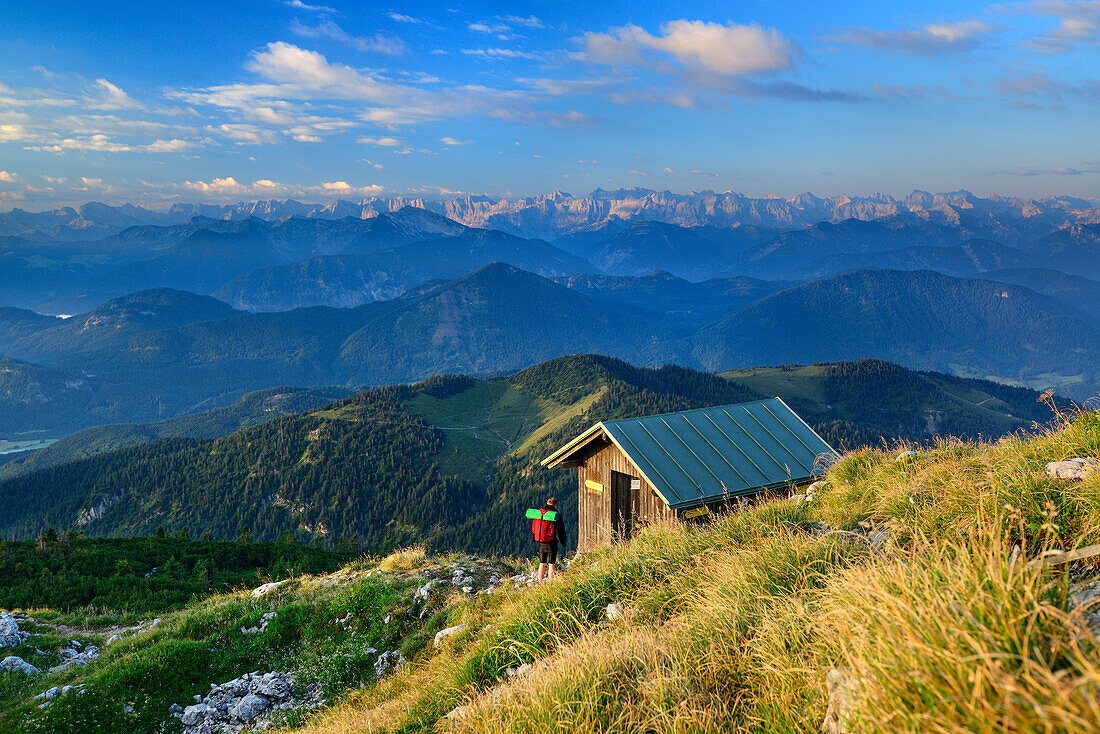 Wanderer erreicht Biwakhütte am Gipfel der Benediktenwand zu, Karwendel im Hintergrund, Bayerische Voralpen, Oberbayern, Bayern, Deutschland
