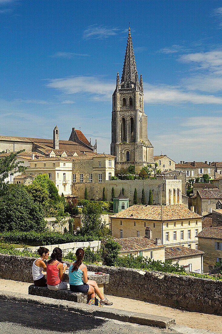 Saint-Emilion, in the Dordogne River Valley, Gironde region, Acquitaine, France, overview with houses and tower of Romanesque monolithic church ´L´Eglise Montlithe´, three young women playing cards, May