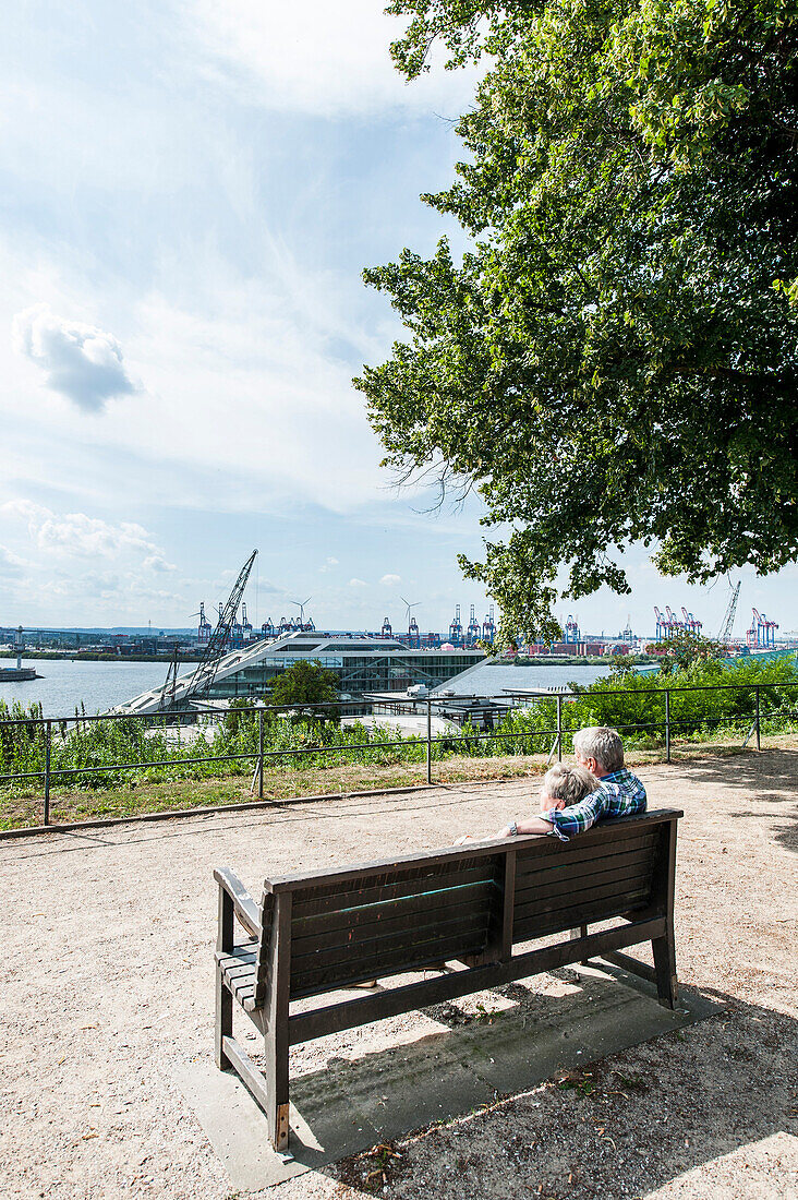 Paar sitz auf einer Parkbank in den Altonaer Terrassen und schaut auf den Hamburger Hafen, Hamburg, Deutschland