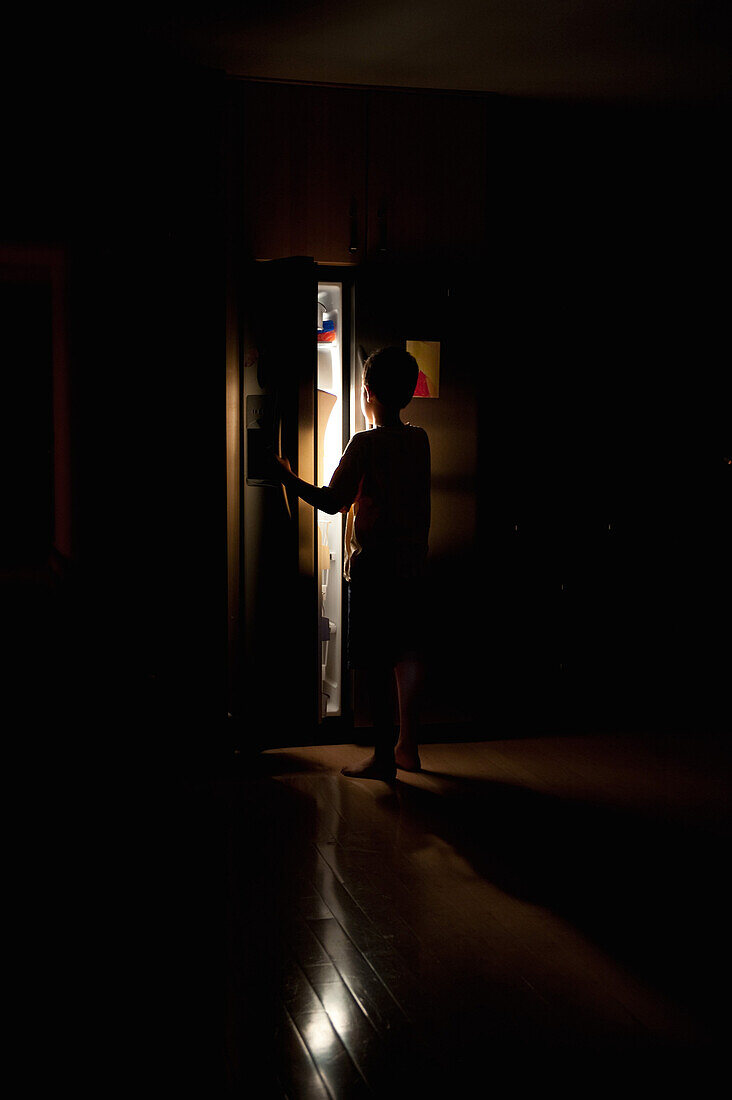 Boy Looking in Refrigerator in Dark Kitchen