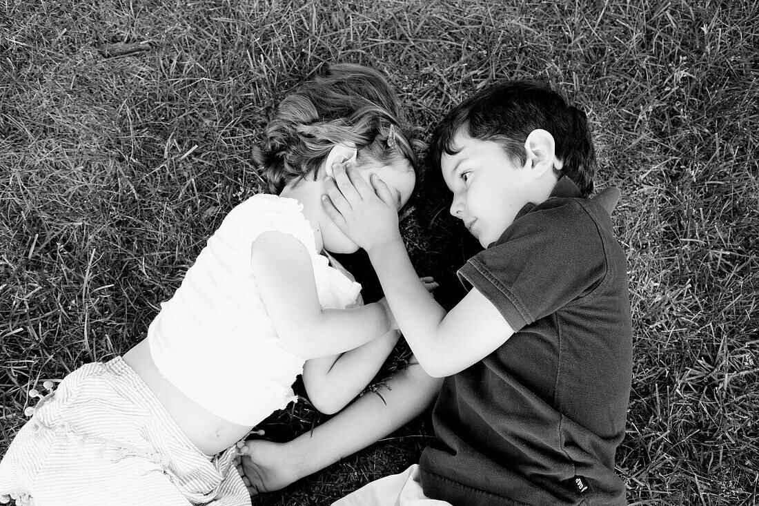 Young Boy and Girl Laying on Grass