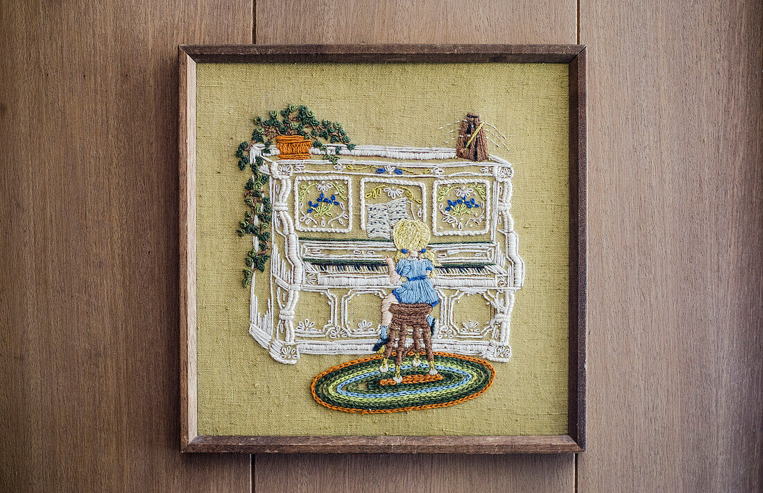 Framed Embroided Girl Playing Piano on Wood Panelled Wall