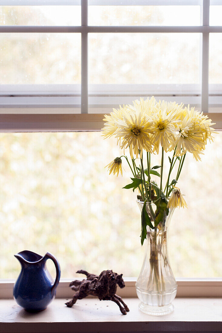 Bouquet of Yellow Flowers in Vase Next to Horse Sculpture, and Blue Creamer