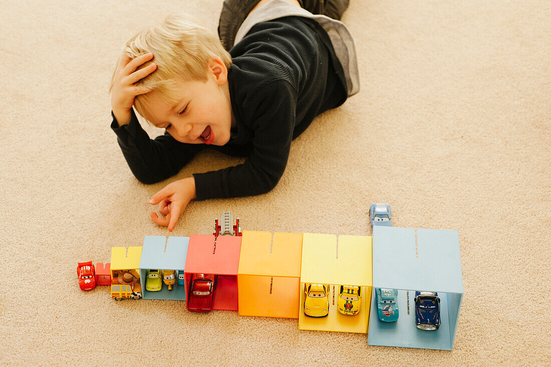 Young Boy Playing with Boxes and Toy Cars