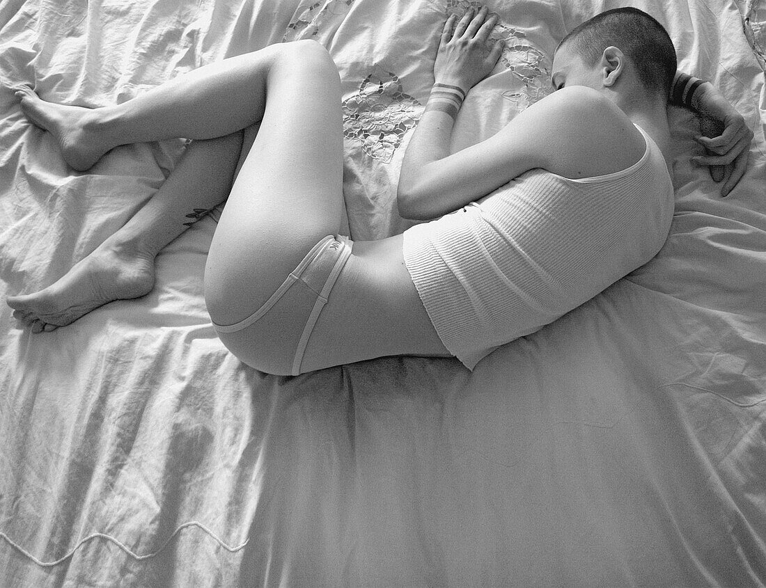 Junge Frau in Unterwäsche auf dem Bett schlafend, hoher Blickwinkel