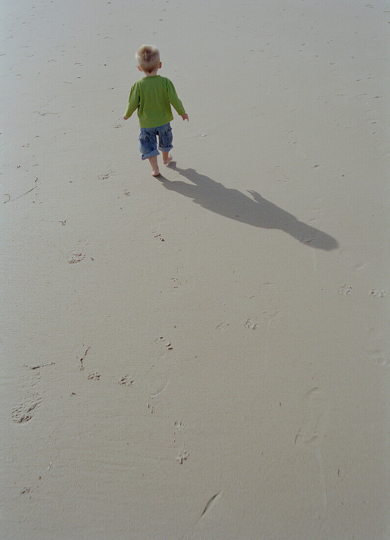Young Boy Walking on Beach, Rear View