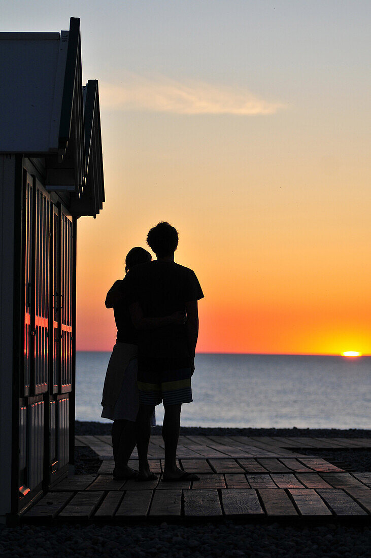 Couple On The Beach Embracing Near Beach Huts At Sunset, Boardwalk Of Cayeux-Sur-Mer, Bay Of Somme, Somme (80), France
