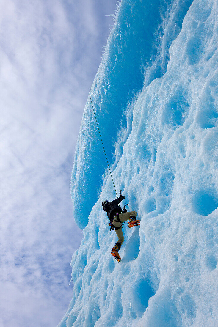 An Ice Climber Ascends The Face Of A Large Iceberg Frozen Into Mendenhall Lake, Juneau, Southeast Alaska, Winter