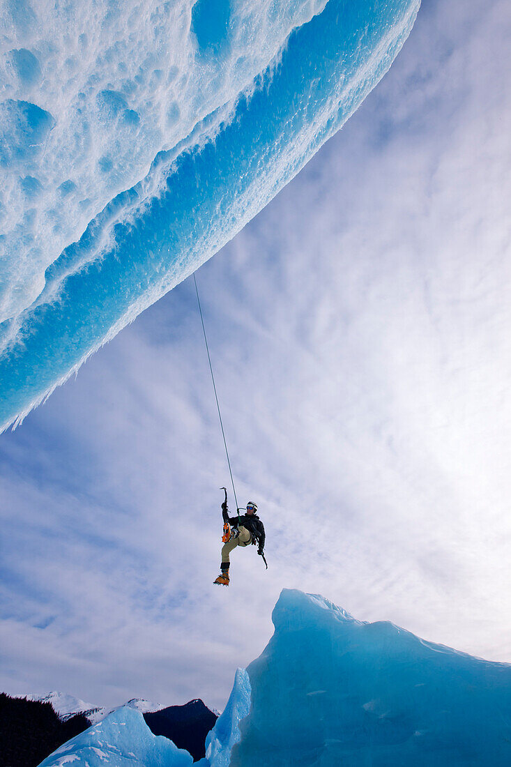 An Ice Climber Swings Down From Rope To Reach Face Of A Large Iceberg Frozen Into Mendenhall Lake, Juneau, Southeast Alaska, Winter
