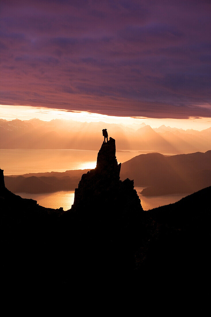 Female Hiker Standing On Peak Overlooking Lynn Canal & Berner's Bay Near Juneau Alaska At Sunset