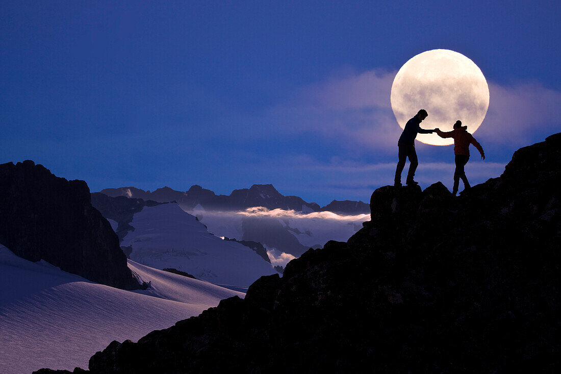 Composite: Hikers Silouetted On A Ridge Above The Juneau Ice Field With The Full Moon In The Background, Southeast Alaska