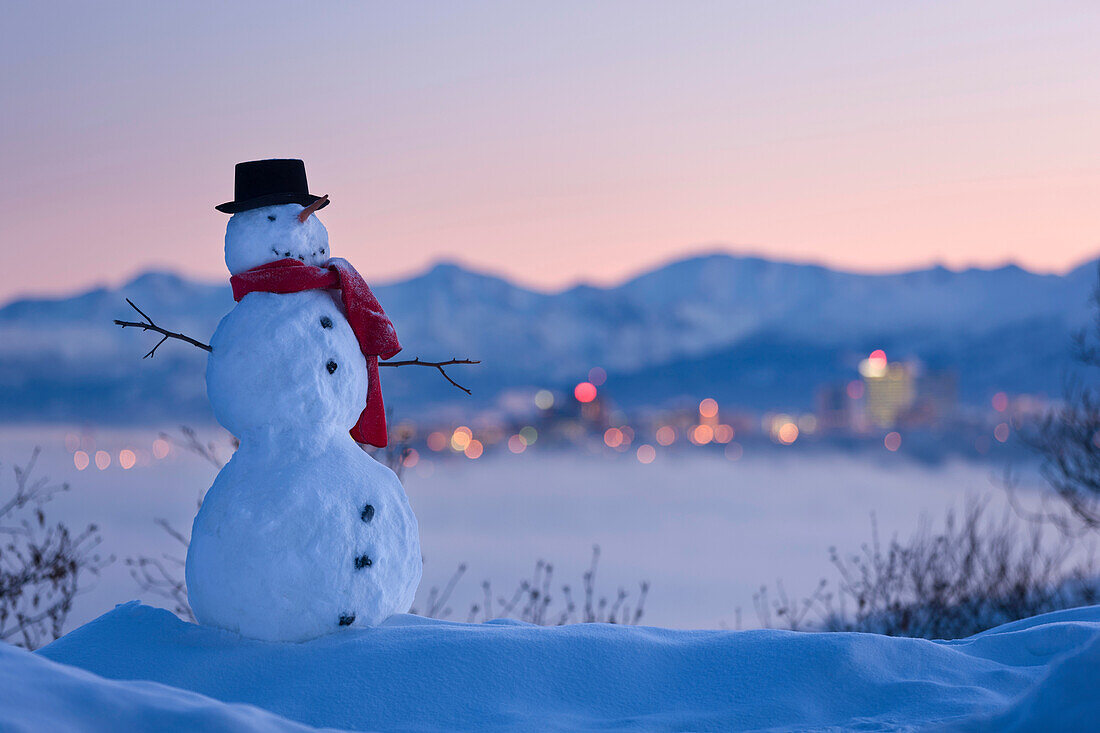'Snowman in front of downtown skyline at dawn knik arm and chugach mountains in the background;Anchorage alaska usa'