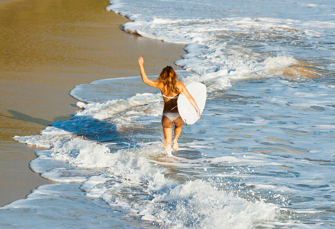 'Spain, Andalusia, Cadiz Province, Woman running along beach with surfboard; Tarifa'