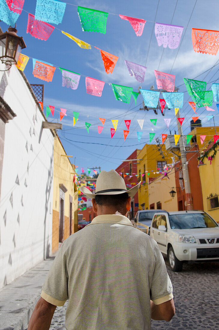 'Mexico, Guanajuato, Man Walking Under Colorful Street Decorations; San Miguel De Allende'