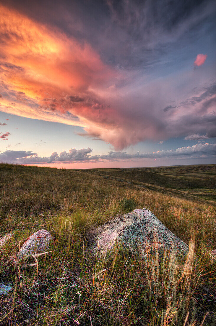'Clouds Lit At Sunset With Some Glacial Erratics Lying In Grasslands National Park;Saskatchewan Canada'