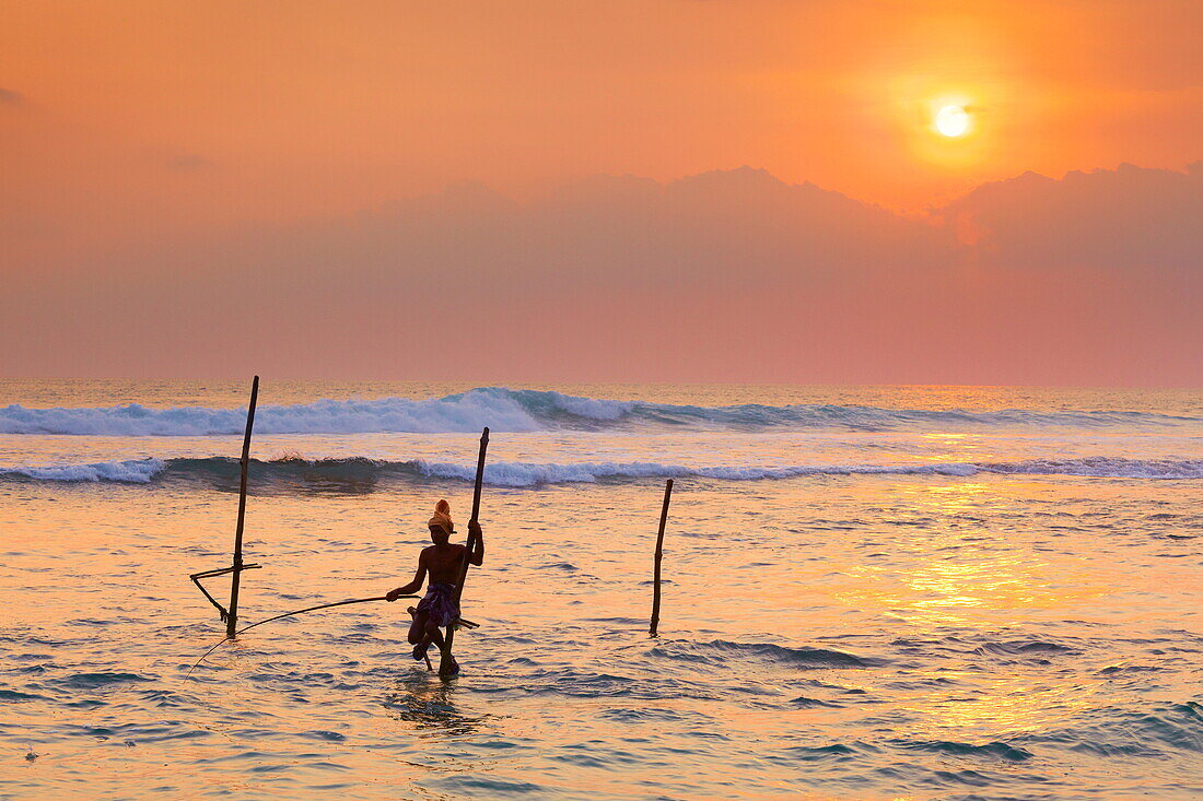 Sri Lanka - fisherman catches fish at sunset time, Koggala Beach, south part of Sri Lanka, Indian Ocean coast, Asia