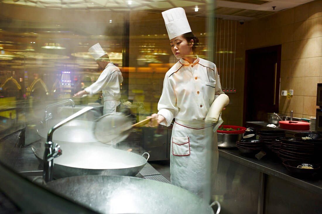A chef preparing and cutting hand cut noodles into a vat of boiling water