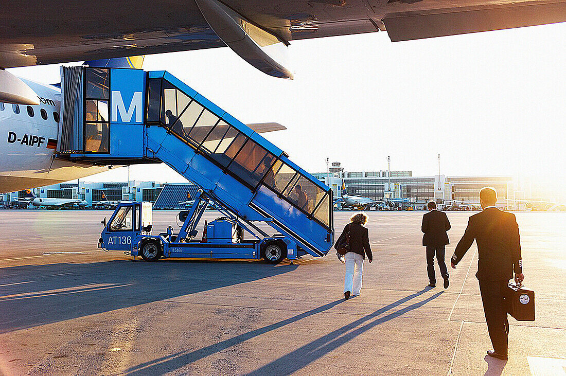 Businessmen and travelers board a plane on the tarmac at sunset