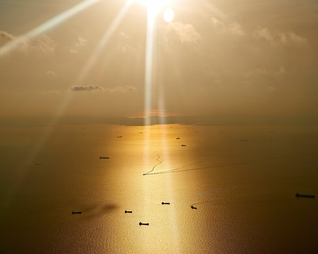 Freight ships sail in the ocean on a bright orange warm day