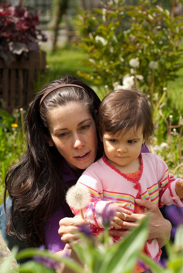 Mother And Child Looking At Flowers Outside In A Garden, Vancouver British Columbia