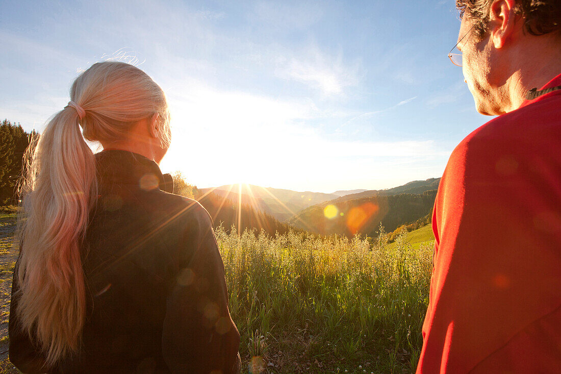 Couple looking at a sunrise above an alpine pasture, Styria, Austria