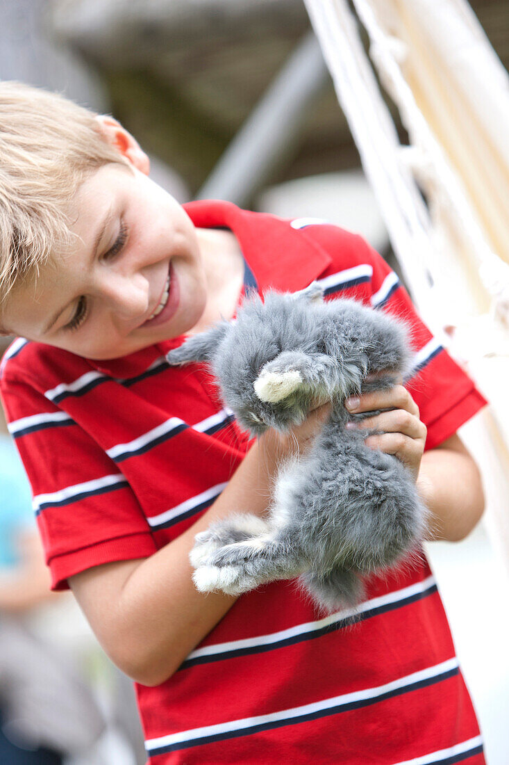 Junge (7 Jahre) hält ein Kaninchen, Steiermark, Österreich