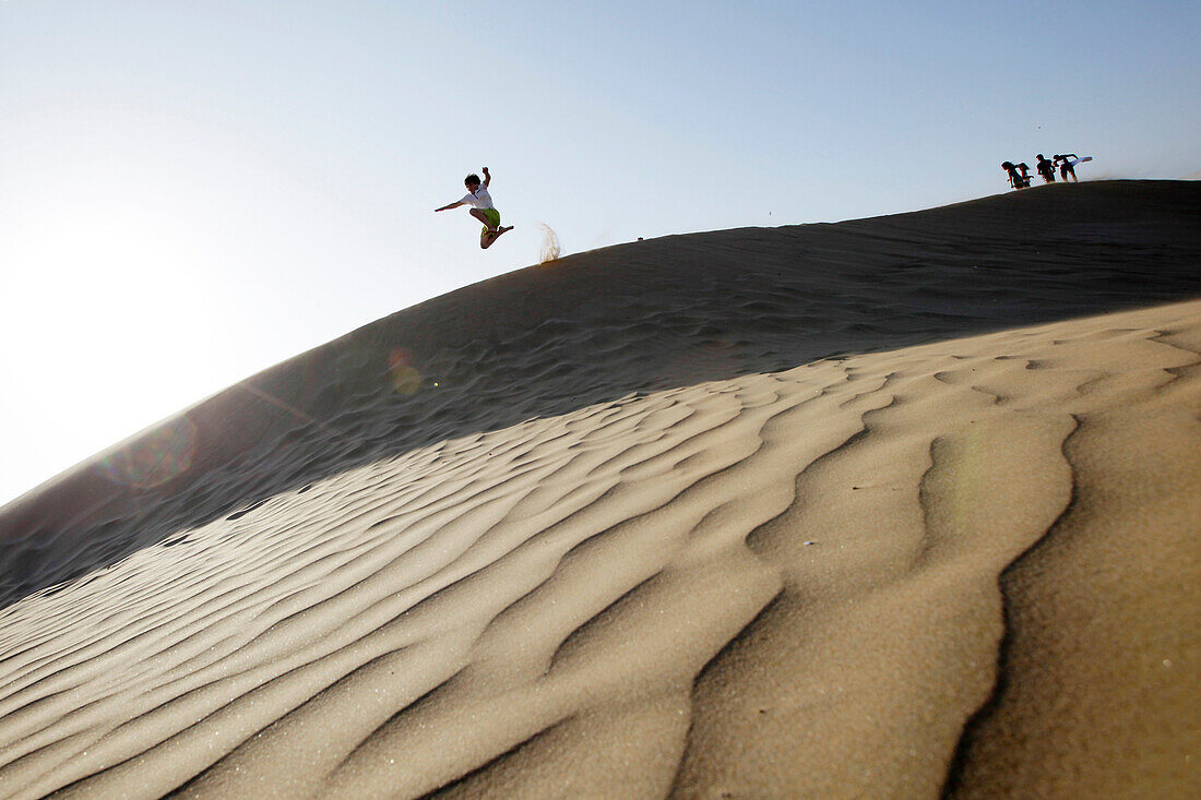 Boy jumping from a sand dune, Agadir, Morocco