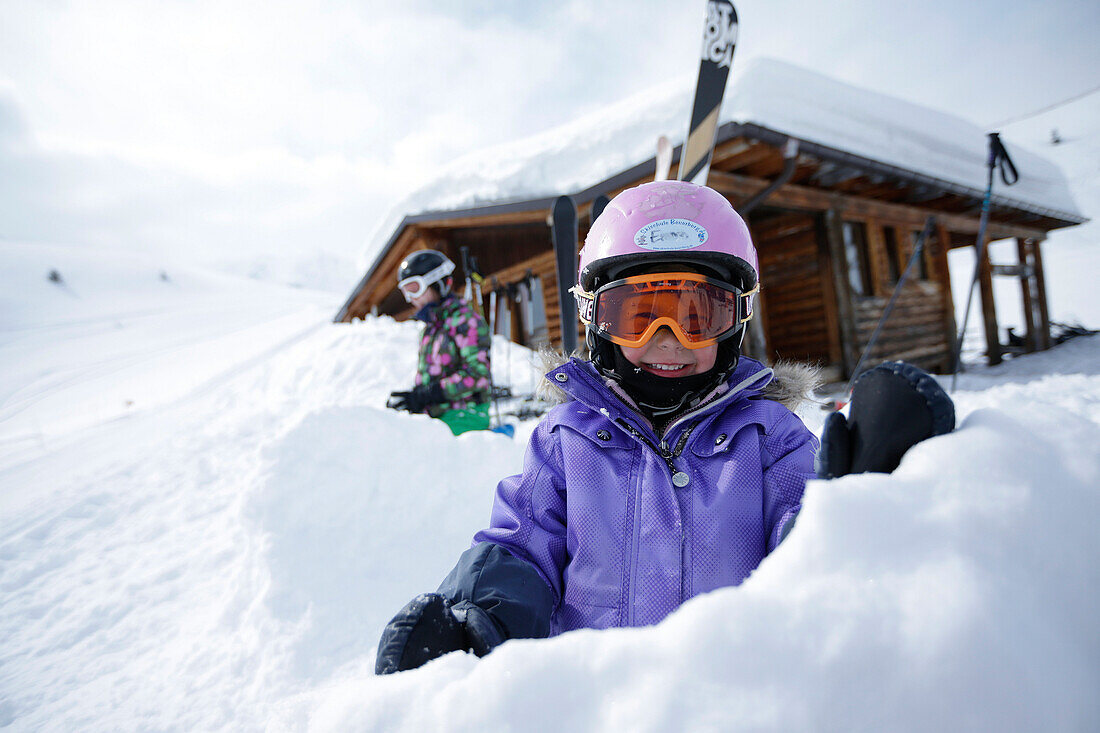 Two children in snow in front of a hut, ski resort Ladurns, Gossensass, South Tyrol, Italy