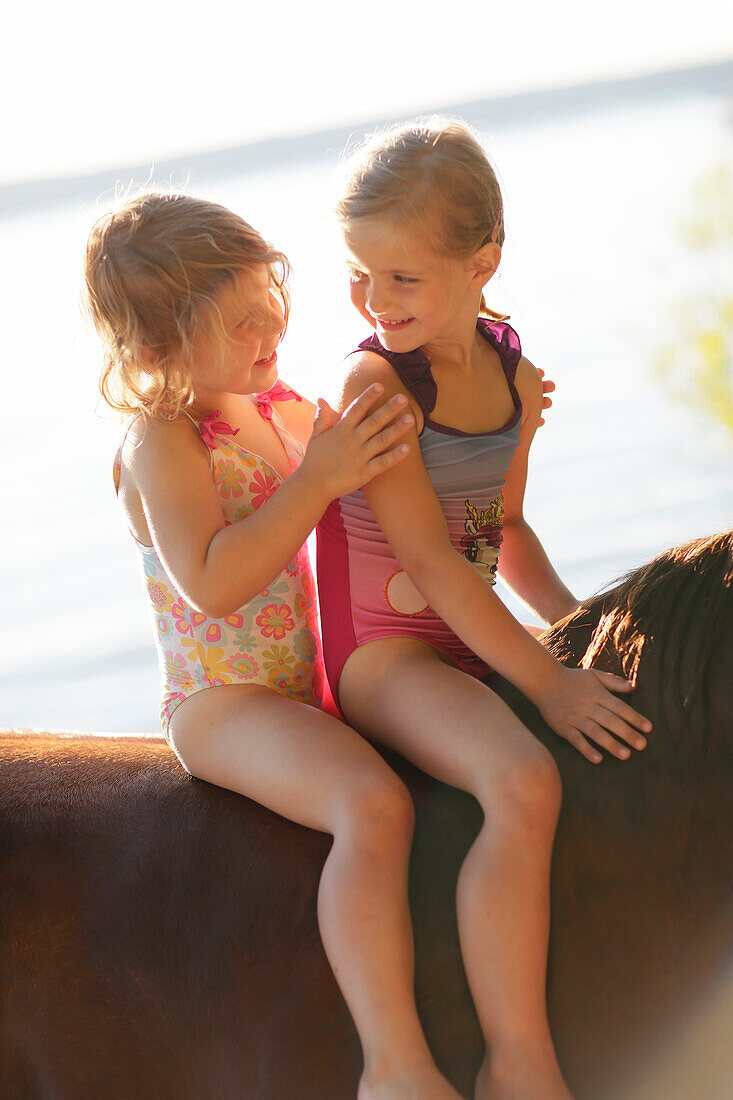 Two girls riding a horse at lake Starnberg, Ammerland, Munsing, Upper Bavaria, Germany