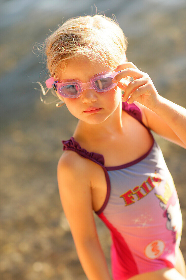 Girl (4 years) wearing swimsuit and swim googles at lake Starnberg, Ammerland, Munsing, Upper Bavaria, Germany