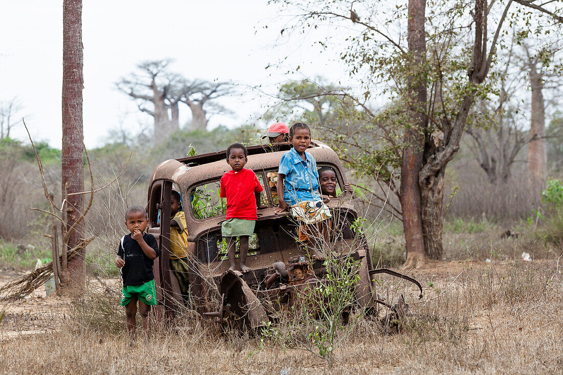 Children playing on a wrecked car near Morondava, West Madagascar, Africa