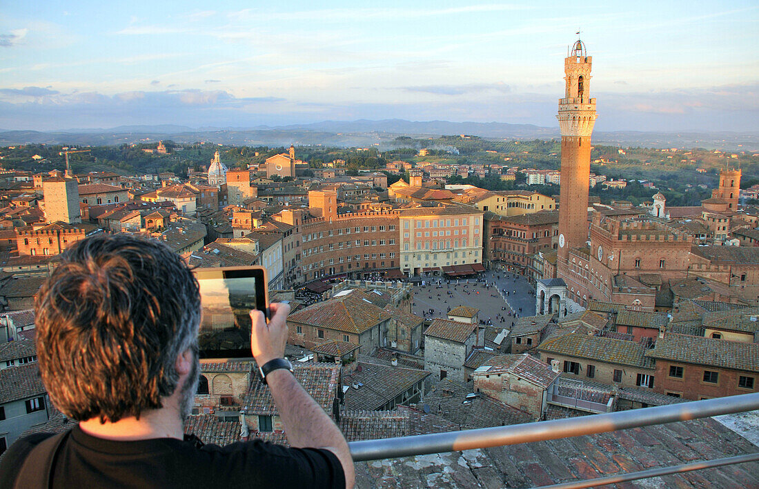Person taking a photograph of the town hall and the Piazza del Campo from the cathedral museum, Siena, Tuscany, Italy