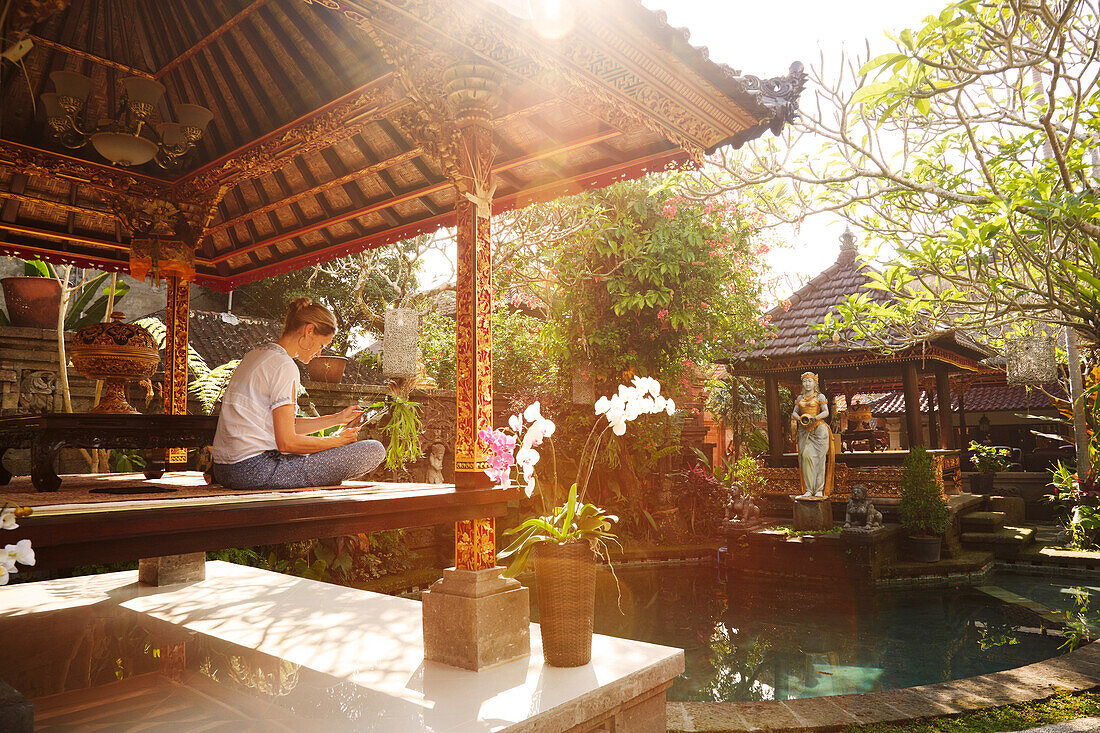 Frau sitzt in einem Pavillion und liest, Ubud, Bali, Indonesien
