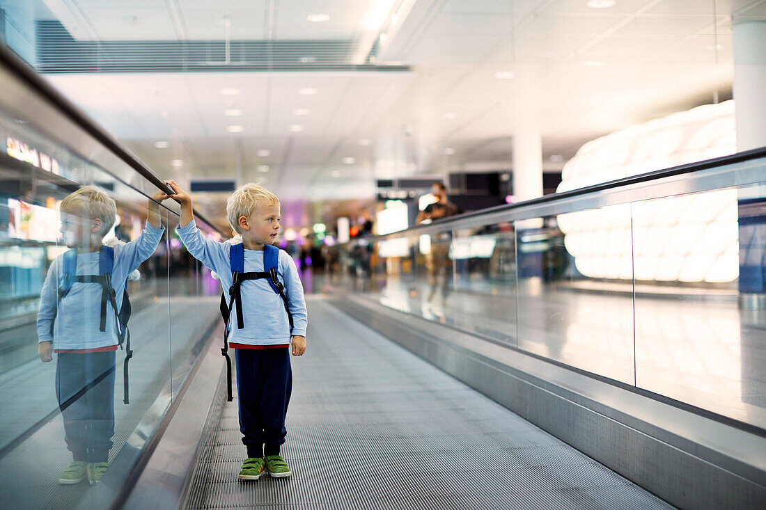 Boy standing on a moving walkway at airport