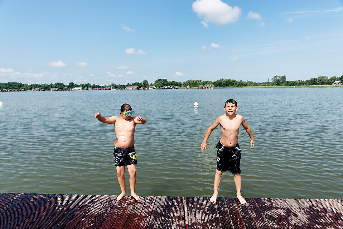 Two boys jumping baclwards into the lake, Inselsee, Guestrow, Mecklenburg-Western Pomerania, Germany