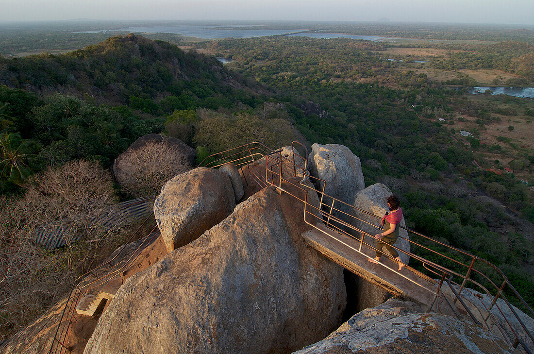 Female tourist walking on top of the Aradhana Gala Rocks on Mihintale mountain, Mihintale near Anuradhapura, Kultur Dreieck, Sri Lanka