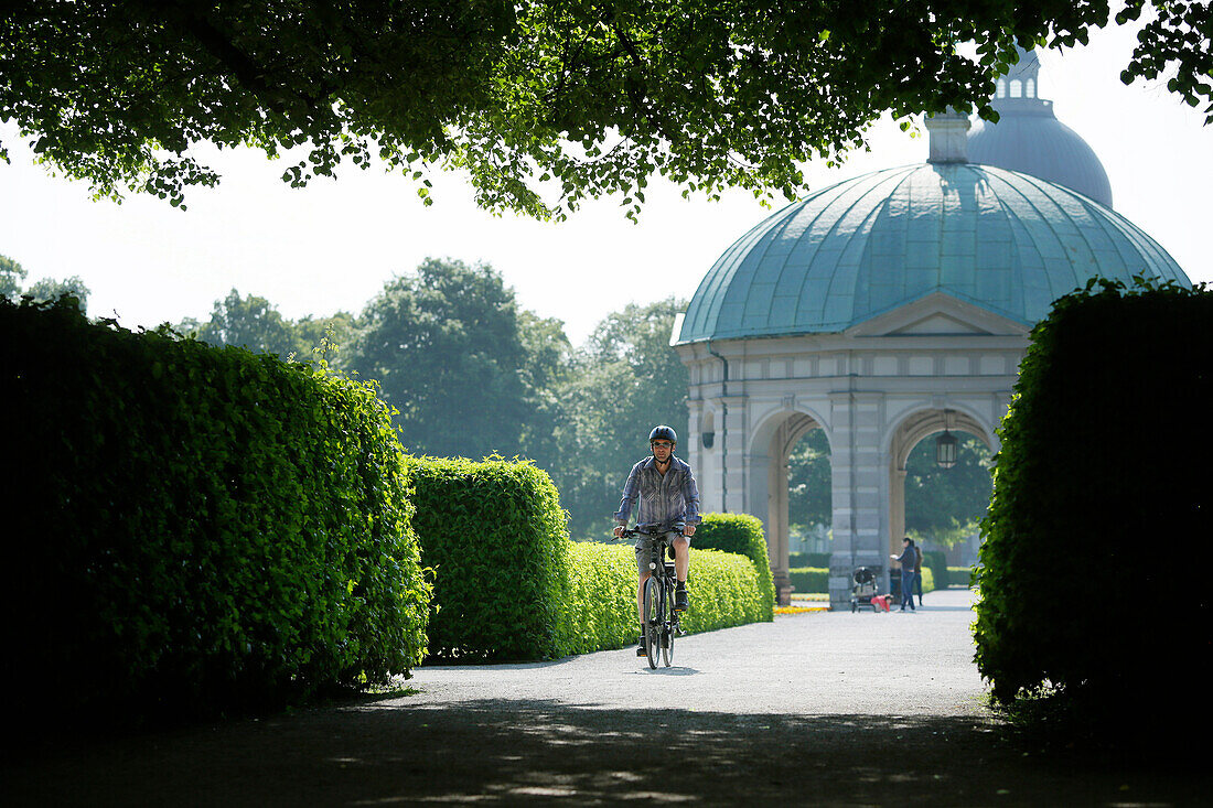 Man riding an e-bike through Hofgarten, Munich, Upper Bavaria, Germany