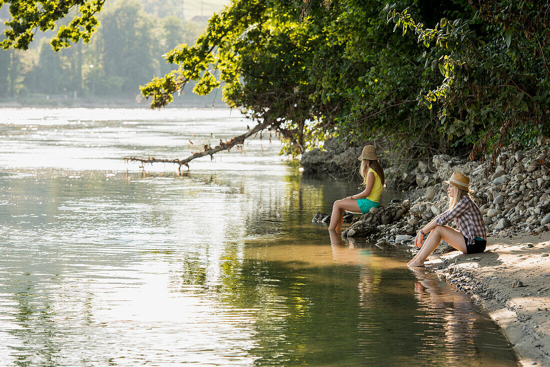 Two young women sitting at river Rhine, Rheinfelden, Baden-Wuerttemberg, Germany