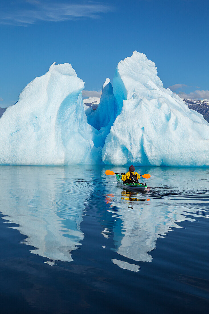 A sea kayaker paddles beside an iceberg in Southeast Alaska's Stephens Passage on a summer evening, Holkham Bay, Tracy Arm. MR_Ed Emswiler, ID#12172012A