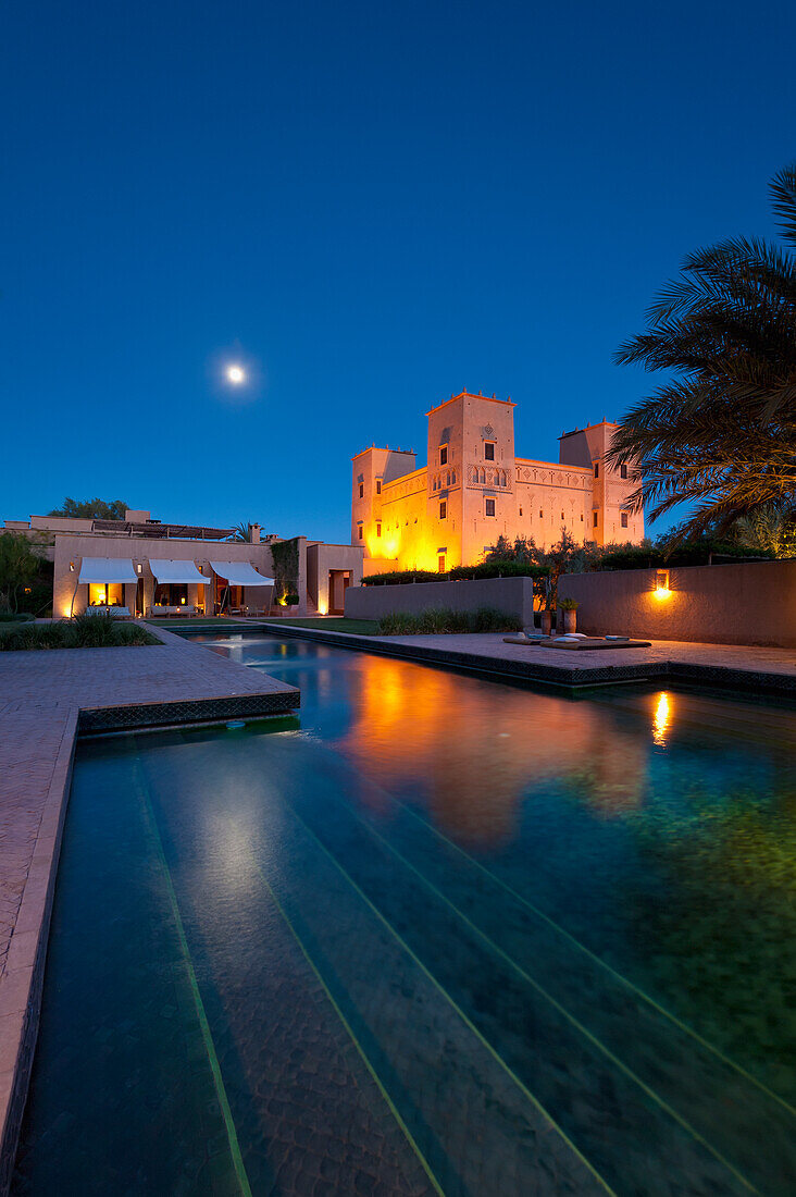 Moon rising above swimming pool and main kasbah of Dar Ahlam Hotel, Skoura, Morocco
