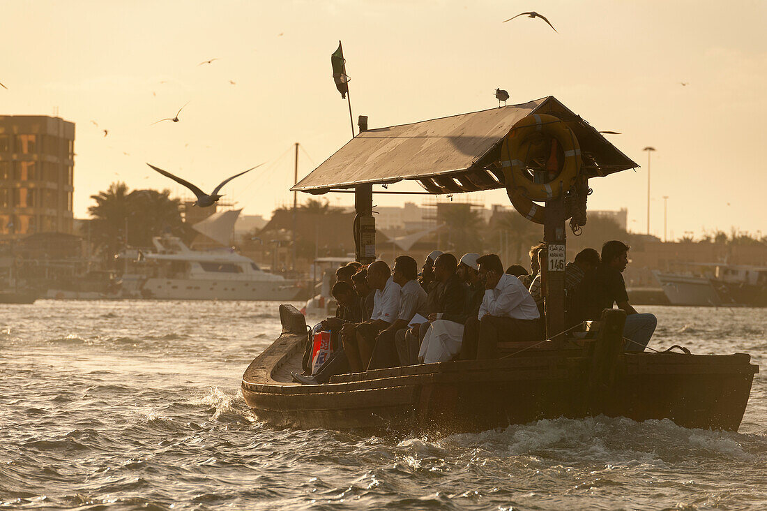 People on water taxi at dusk at the Creek, Dubai, UAE