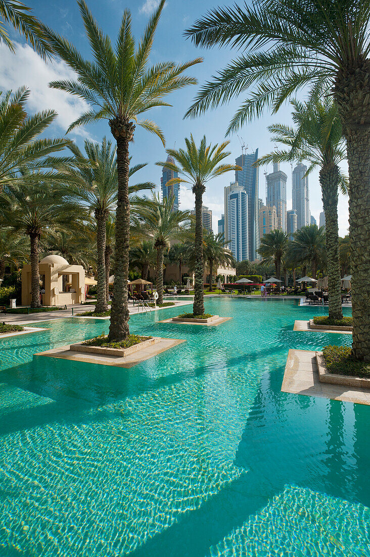 Swimming pool of One and Only Royal Mirage with tower blocks behind, Dubai, UAE