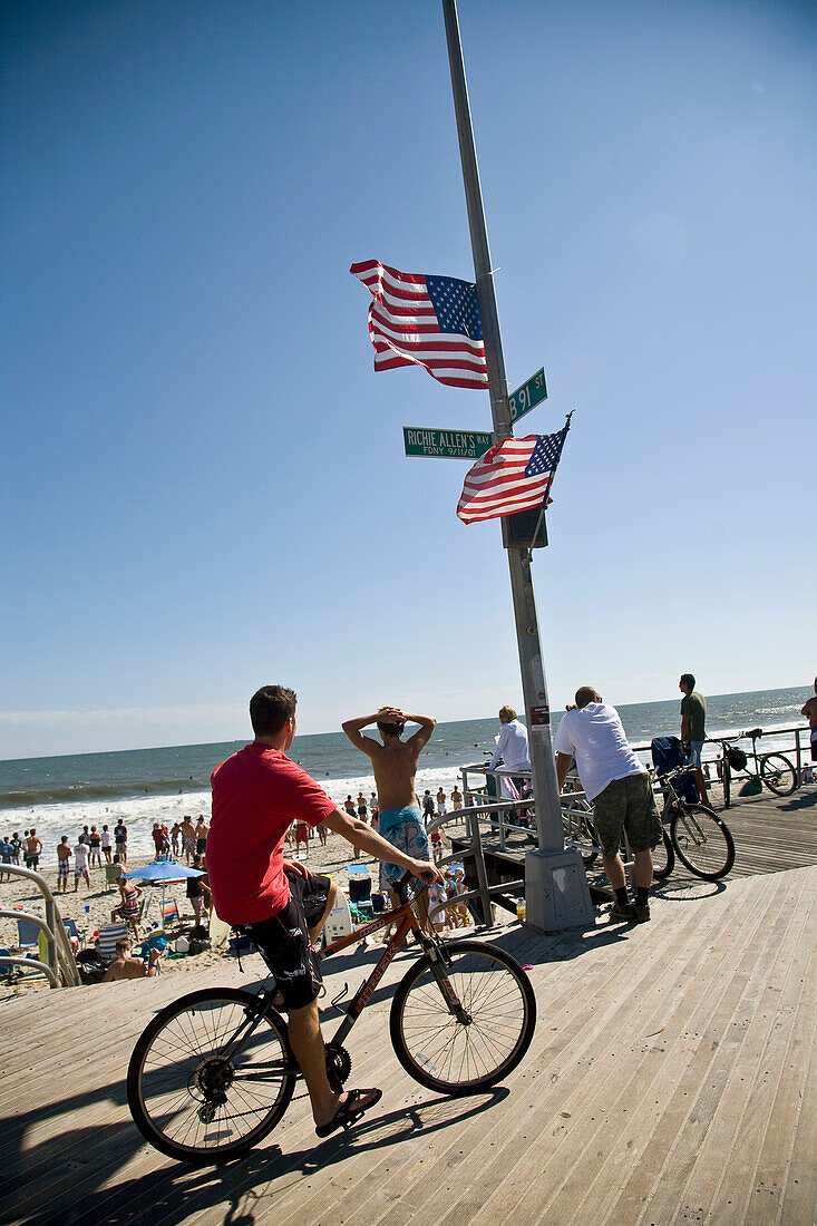 USA, New York State, People and cyclist on boardwalk, Rockaway