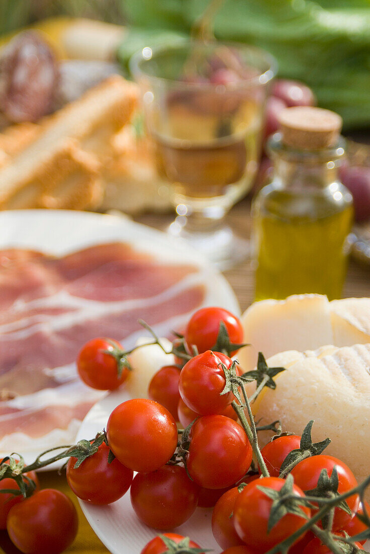 Prosciutto Ham, Cheese, Tomatoes, White Wine And Other Ingredients For Picnic, Tuscany, Italy.